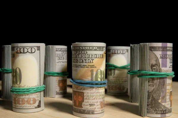 En hel del dollar pengar rullas upp i ett rör, på en svart bakgrund — Stockfoto