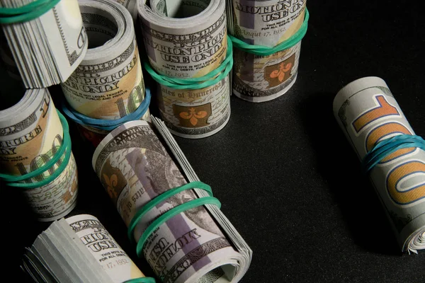 Πολλά δολάρια χρήματα τυλιγμένα σε ένα σωλήνα, σε μαύρο φόντο — Φωτογραφία Αρχείου