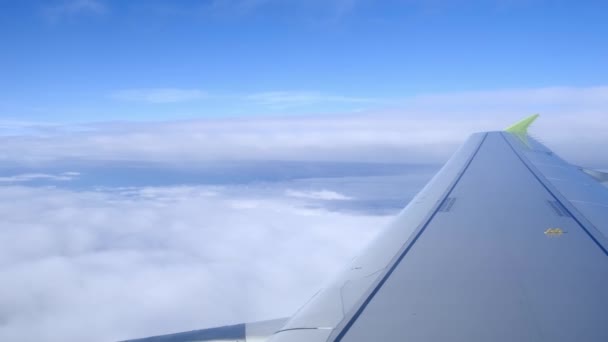 Flügel eines Flugzeugs im Sinkflug durch dicke Wolken mit klarem blauen Himmel, ein Flugzeug landet. — Stockvideo