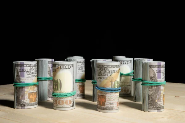 Πολλά δολάρια χρήματα τυλιγμένα σε ένα σωλήνα, σε μαύρο φόντο — Φωτογραφία Αρχείου
