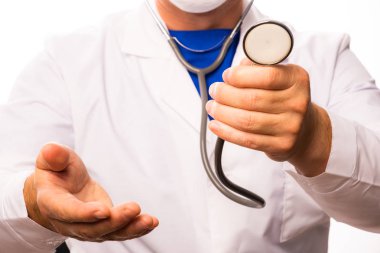 Steteskoplu maskeli bir doktor hastalara yardım etmek için elini yudumluyor..