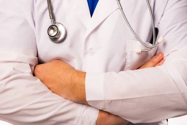 Beyaz elbiseli bir doktor elleri göğsünde katlanmış şekilde duruyor, boynunda asılı bir stetoskop. Yakın çekim