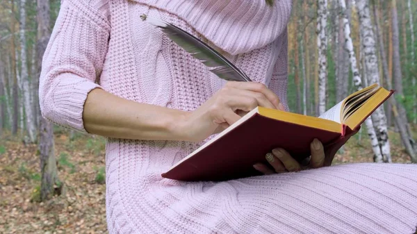 Heureuse femme souriante attrayante écrit de la poésie avec plume dans la forêt de printemps . — Photo