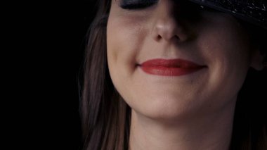 Siyah cadı şapkalı, parlak kırmızı dudakları gülümseyen çekici gizemli bir kadının yarım taraflı yüzünün yakın çekim. Cadılar Bayramı konsepti.