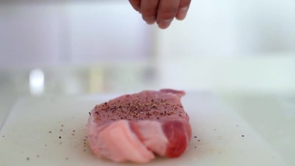 Посыпает перец на сырое мясо, крупным планом в замедленной съемке. Посыпать перец на стейк из сырого мяса, крупным планом в замедленной съемке. Подготовка пищи и использование . — стоковое видео