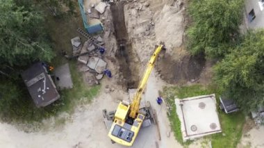 Kazıcı ve işçiler bir boru çukuru kazıyor