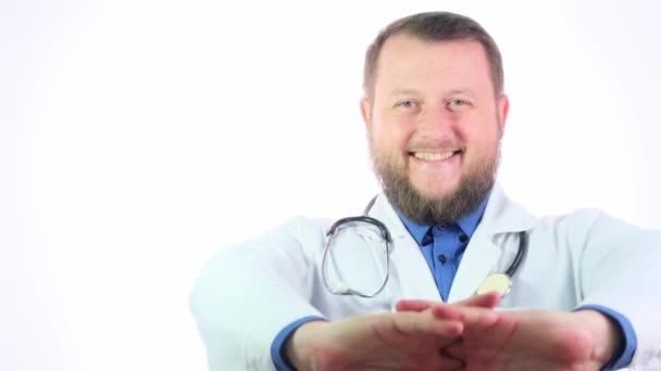 Niza gordito médico con una barba en un abrigo blanco sobre un fondo blanco aislado — Vídeo de stock