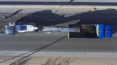 Asfalt değirmeni yoldan asfalt yüzeyini öğütüyor ve bir kamyona yüklüyor, hava manzaralı.