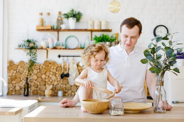 Baba ve kızı mutfakta mısır gevreğiyle oynuyorlar. Montessori eğitimi kavramı. Evde beraberiz. Tüm aile için eğlence..