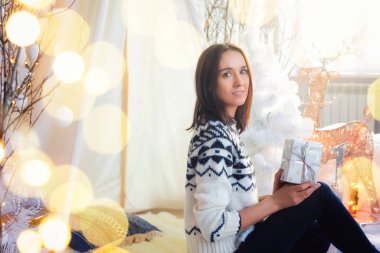 Koyu saçlı mutlu genç bayan Noel ağacının yanında. Yeni yıl konsepti. Hafif Noel dekoru. Bulanık ışık çelenkleri