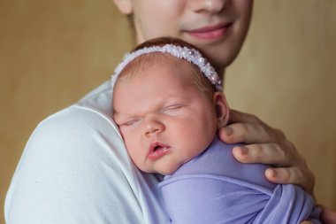 Mutlu, genç bir babanın şirin, tapılası yeni doğmuş kızına sarılışının yakın plan portresi. Kapalı alan çekimi, konsept görüntü