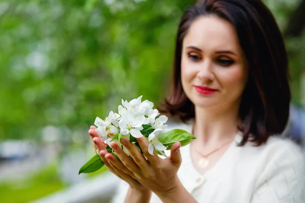 A bouquet of spring flowers in the hands of a girl on the background of a pink sweater. Blooming Apple tree in the Park in spring. Soft focus. To close.