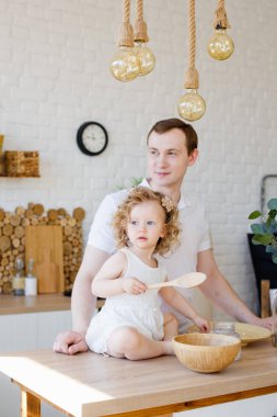 Beyaz bir baba ve kızı, komik bir baba ve kız mutfakta sarılıp yemek yapıyorlar. Parlak bir mutfak, yaşam tarzı ve babalar günü, bekar ebeveynler günü.