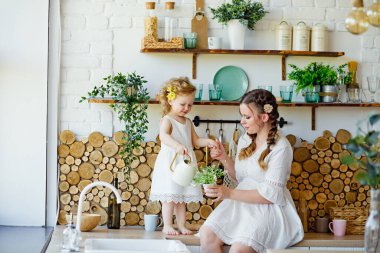 Masadaki mutfakta oynayan küçük bir kız çocuğu. Mutlu aile annesi ve çocuğu, kızı evde yemek hazırlıyor. Oyunda bir çocuk yetiştirmek.