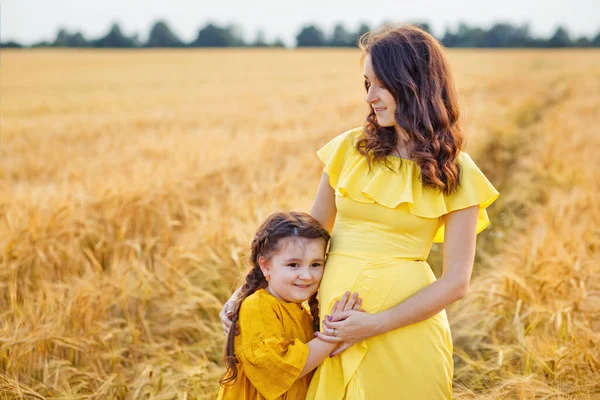 幸せな家族 彼女の小さなかわいい娘が晴れた夏の日に小麦のオレンジ畑を歩いている若い美しい妊婦 親と子供の関係 国内の自然 — ストック写真