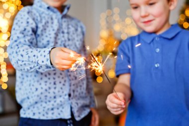 Seçici odaklanma. Çocuklar bir Sparkler tutuyor, yakın plan. Maytap ve kıvılcım saçan Makro fotoğraf festivali arka planı, Noel ve yeni yıl için büyülü atmosfer