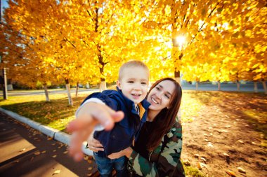 Güz Parkı 'nda bir bankta oturan güzel anne ve oğul. Açık hava fotoğrafları. Ebeveynler ve çocuklar arasındaki ilişkiler. Anneler Günü.
