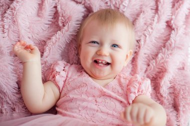 Pembe kabarık bir battaniyenin üzerinde uzanan sevimli bir kızın portresi, çocuk fotoğrafçılığı konsepti