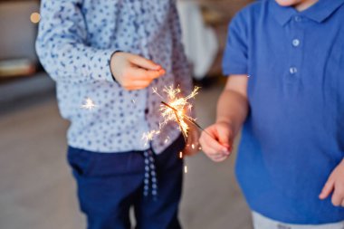 Seçici odaklanma. Çocuklar bir Sparkler tutuyor, yakın plan. Maytap ve kıvılcım saçan Makro fotoğraf festivali arka planı, Noel ve yeni yıl için büyülü atmosfer