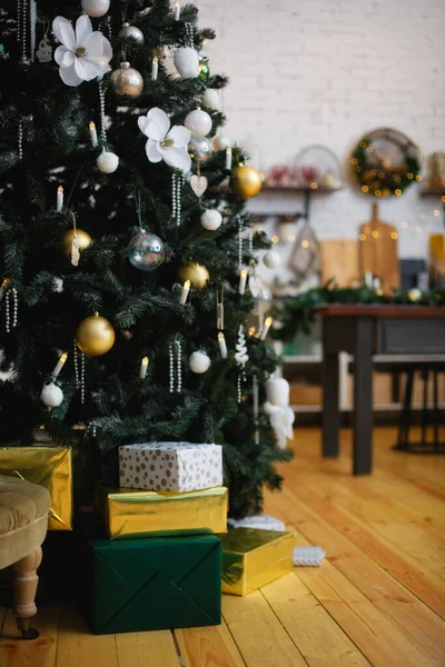 Stylish living room interior with decorated Christmas tree and comfortable armchair.