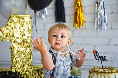 Sarışın bir çocuk doğum gününde. Siyah ve altın renkli ilk pastayla süslenmiş fotoğraf bölgesi. Çörek..