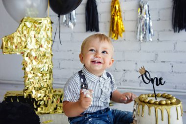 Sarışın bir çocuk doğum gününde. Siyah ve altın renkli ilk pastayla süslenmiş fotoğraf bölgesi. Çörek..
