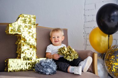 İlk doğum gününde, altın, siyah ve gümüş renkli bir partide tatlı sarışın çocuk..