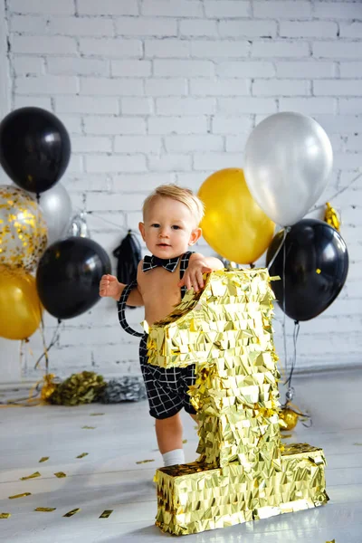 İlk doğum gününde, altın, siyah ve gümüş renkli bir partide tatlı sarışın çocuk. Altın numarayı tutuyor..