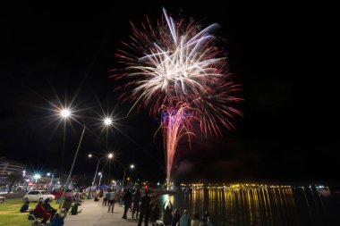 Kişilik bir kalabalık yukarıda gece gökyüzünde bir liman kenarında patlama havai fişekler. Tauranga, Yeni Zelanda, 7 Şubat 2015 fotoğrafı 