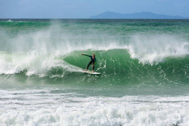 Yeni Zelanda'nın en popüler sörf plajlarından biri olan Maunganui Dağı'nda dalgaya binen bir sörfçü. Arka planda Mayor Island var. 15 Ekim 2013