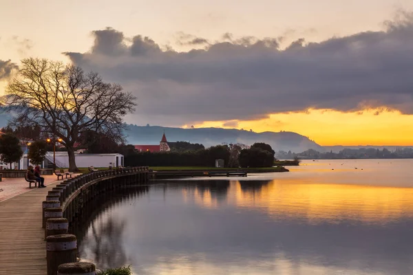 Rotorua, Yeni Zelanda. Göl kenarındaki kaldırımdan gün batımında Rotorua Gölü manzarası 