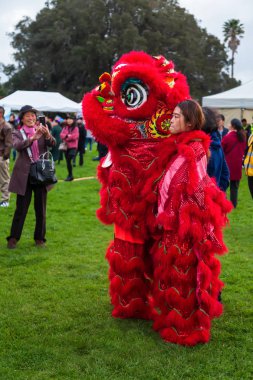 Bir çift Çinli aslan dansçısı, biri parlak kırmızı kostümden dışarı bakıyor, Auckland, Yeni Zelanda'daki ay (sonbahar ortası) festival kutlamalarında. 13 Eylül 2019 