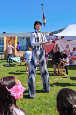 Çizgili siyah beyaz kostümlü erkek stilt walker, hokkabazlık kulüpleri. 21 Eylül 2019 'da Tauranga, Yeni Zelanda' da bir panayırda çekilmiş. 