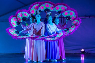Koreli kadınlar yapay ışıklandırma altında sahnede buchaechum ya da fan dansı yapıyorlar. Geleneksel Hanbok elbiseleri giyiyorlar. Auckland, Yeni Zelanda, 14 Eylül 2019 