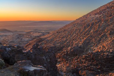 Ruapehu Dağı, Yeni Zelanda, gün batımında. Volkanik yaylaların manzarasına bakan kayalık yamaçlardan bir manzara