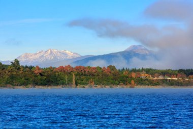 Taupo Gölü, Yeni Zelanda, sonbaharda. Arka planda Ruapehu, Ngauruhoe ve Tongariro, Tongariro Ulusal Parkı 'nın dağları var.