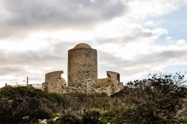 Güneş doğarken uçurumun üstündeki Bonifacio Corsica'deki / daki üzerine kurulmuş antik bir taş değirmen kalıntıları.