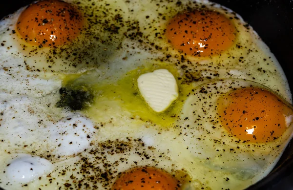 Fried eggs. Close up view of the fried eggs on a frying pan. Salted, spiced and melted butter.