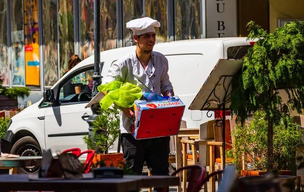 Bucarest, Rumania - 2019. Joven cocinero llevando una caja de verduras —  Fotos de Stock