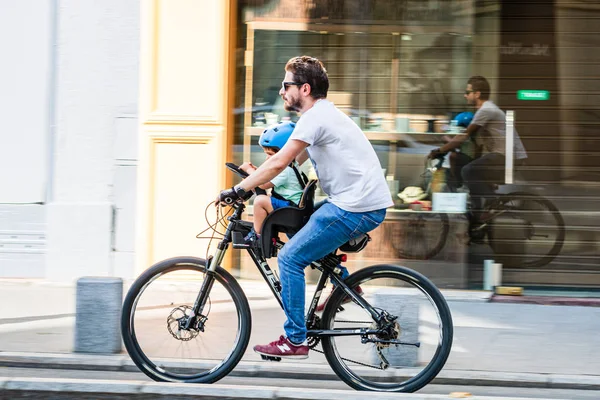 Bucareste, Romênia - 2019. Jovem em uma bicicleta com seu filho — Fotografia de Stock