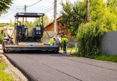 Targoviste, Romanya - 2019. Asfalt makinesinin yanındaki işçiler yatıyordu