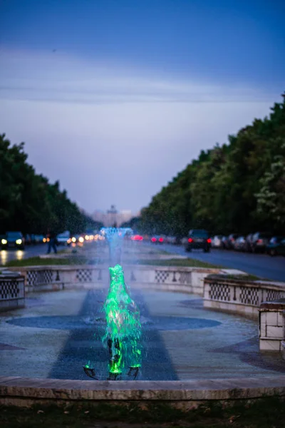 Out of focus image of scenic water fountains and car traffic in — Stock Photo, Image