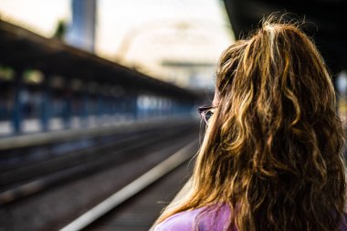 Tren platformunda tek başına yürüyen ve fotoğraf çeken genç kız 