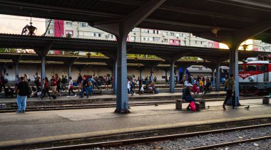 Tren bekleyen yolcular, platfor üzerinde bir bankta oturan