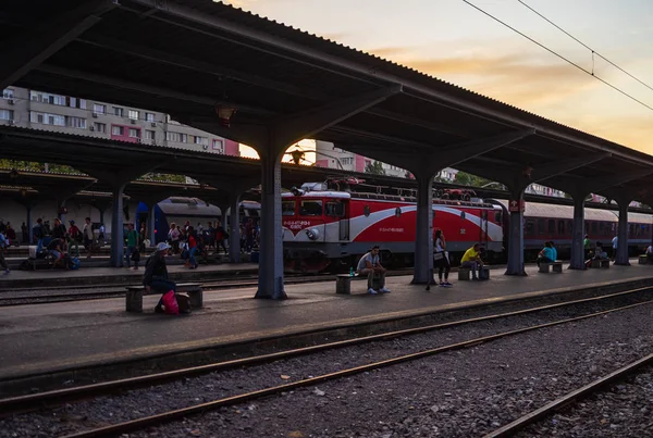 Viajantes esperando por um trem, sentado em um banco na plataforma — Fotografia de Stock
