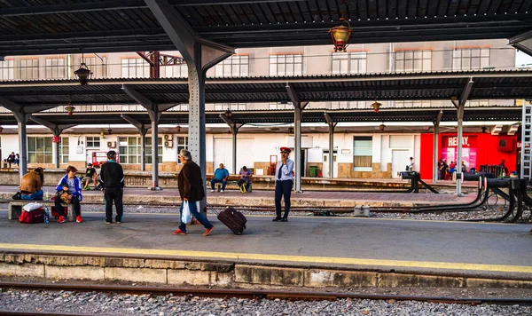 Reizigers wachten op een trein, zittend op een bankje op het platfor — Stockfoto