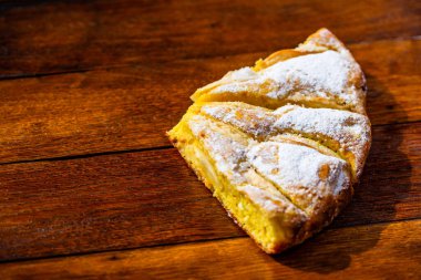 Tahtaya şeker tozu sürülmüş taze pişmiş elmalı turta. Hom