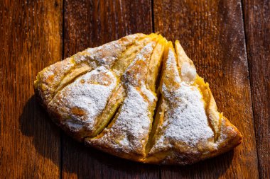 Tahtaya şeker tozu sürülmüş taze pişmiş elmalı turta. Hom