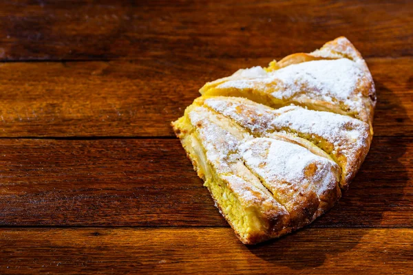 Freshly baked apple pie with sugar powder on a wooden board. Hom