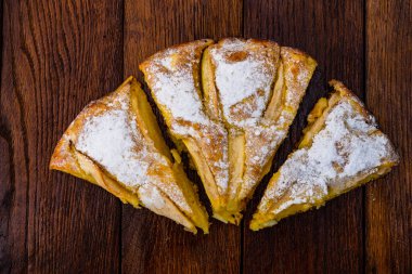 Tahtaya şeker tozu sürülmüş taze pişmiş elmalı turta. Hom